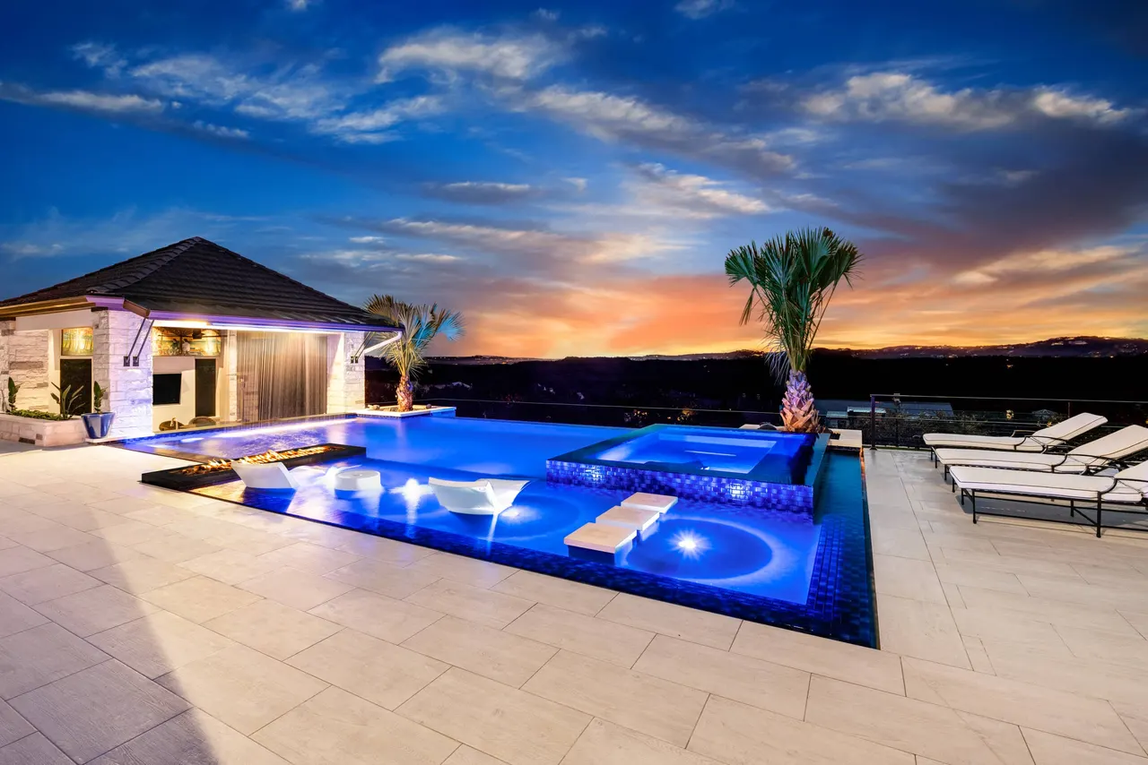 Perimeter-overflow pool and raised glass-tile spa at sunset above the Texas Hill Country, Bee Cave
