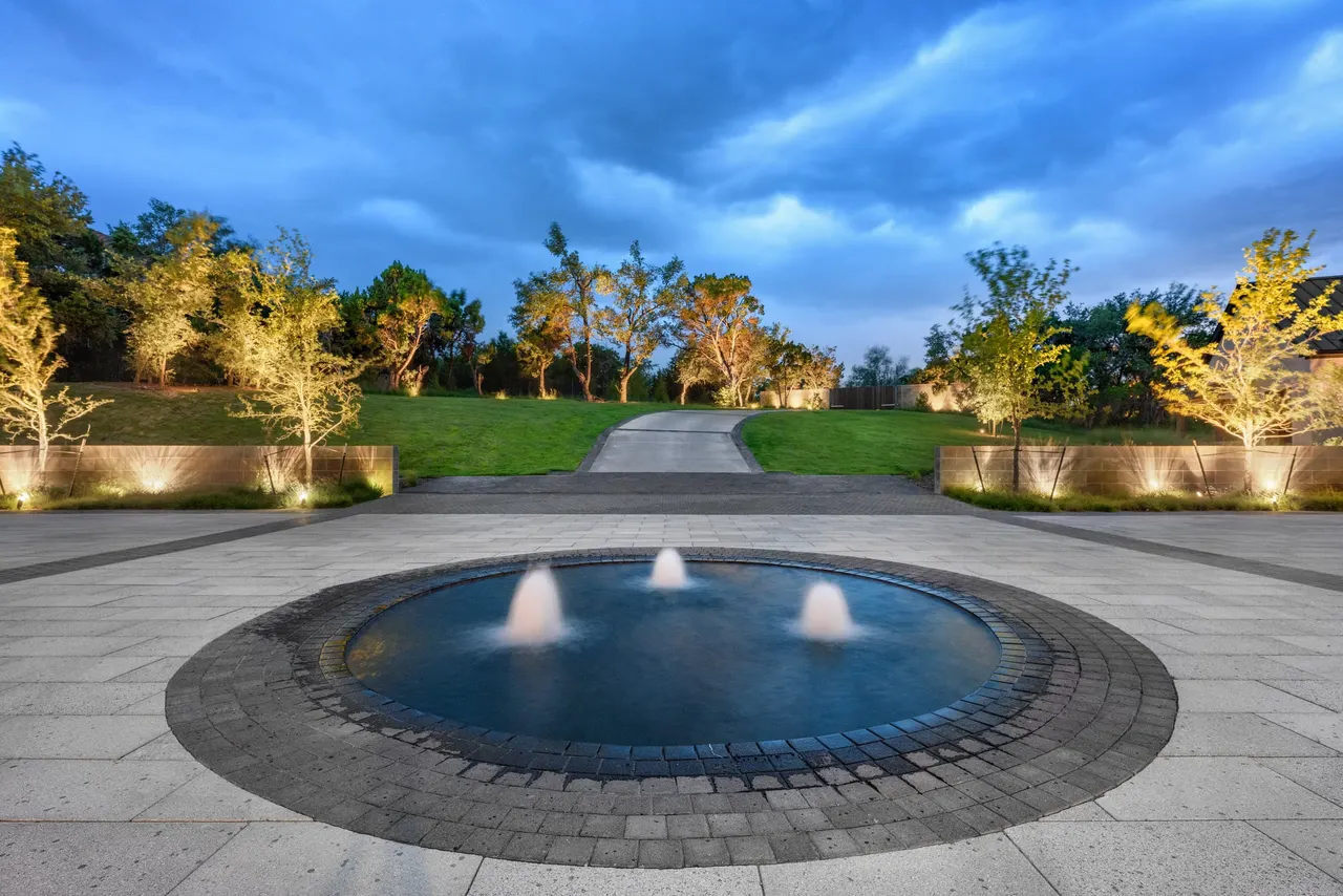 Estate infinity pool with fire bowls and sunken lounge at dusk by GB IV Designs, West Lake Hills