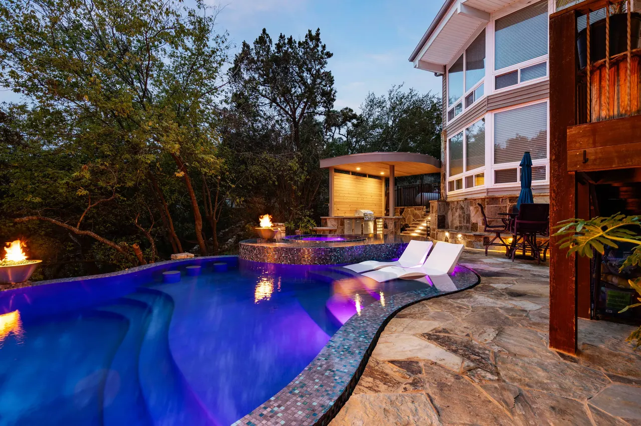 Iridescent glass-tile spa and fire bowls over a Hill Country lake at twilight